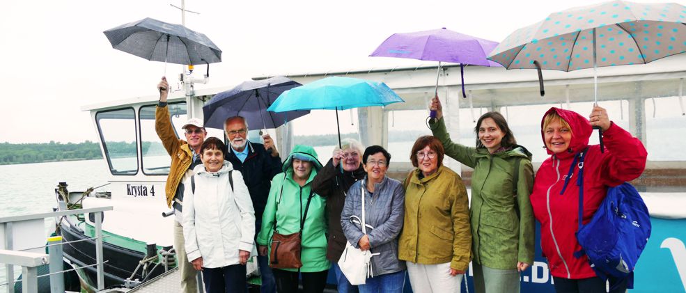 Ehrenamtliche mit Regenschirmen an der Bootsanlegestelle beim Sommerworkshop
